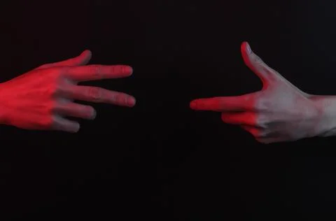 Two hands stretch to each other on a black background with red neon light Stock Photos