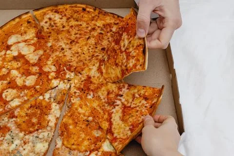 Two hands taking slices pizza from cardboard box Stock Photos