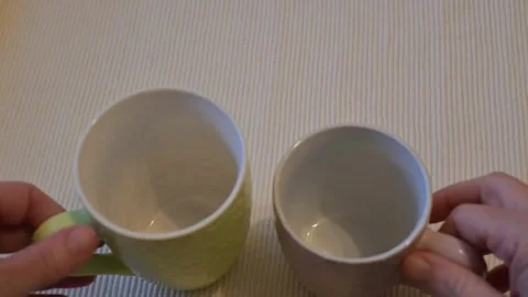 Two hands taking two empty mugs on white background Stock Footage 336061963