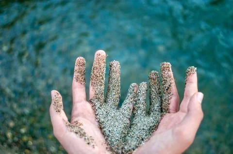 Two Hands Together Partially Covered with Wet Coarse Sand, Water Waves Stock Photos
