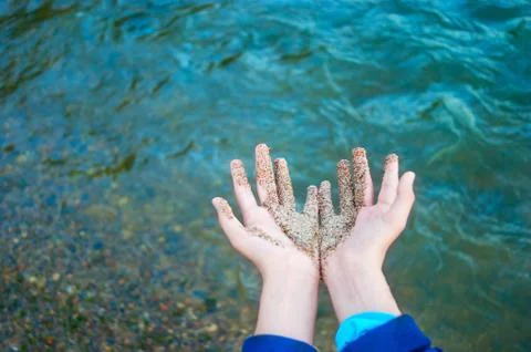 Two Hands Together Partially Covered with Wet Coarse Sand, Water Waves Stock Photos