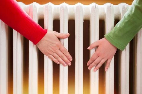 Two hands touch the radiator Stock Photos