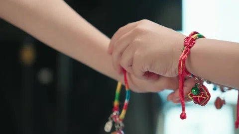 Two Hands Touching Fists Wearing Colorful Bracelets in Indoor Setting Видео 339069131