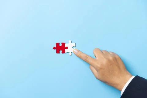 Two hands trying to connect couple puzzle piece on blue background. Teamwor.. Foto stock