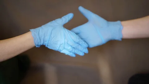 Two hands of two people in blue rubber gloves shake each other Stock-Footage 129632598