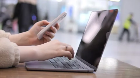 Two hands use phone and laptop simultaneously Stock Footage 341993407