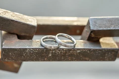 Two hands with wedding rings rest on a strong anchor chain Fotos de archivo