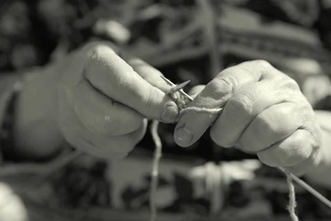 Two hands work with knitting needles and yarn. This activity takes place in a Видео 336464798
