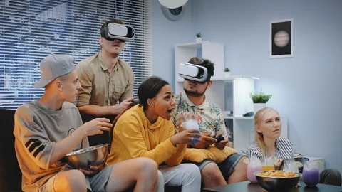 Two handsome boys playing console game in virtual reality glasses among cheerful Stock Footage 112579343