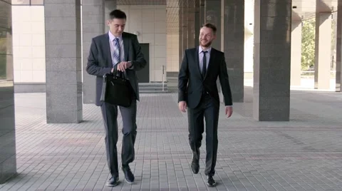 Two handsome businessmen chatting together as they walk along the office Stock Footage