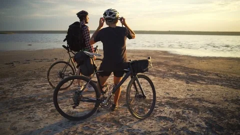 Two handsome cyclists enjoy the sunset with bikes seaside slow motion rapid Stock Footage 78060441