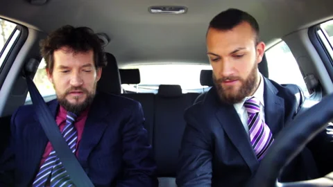 Two handsome elegant man driving car talking Stock Footage 143488061