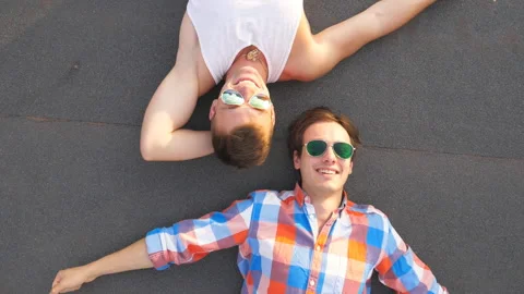 Two handsome gays in sunglasses lying with happiness and joy expression on face Stock Footage 302374449