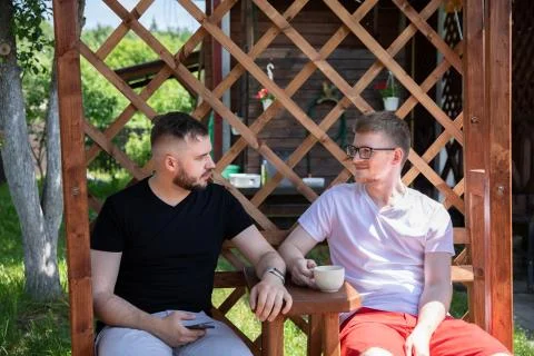 Two handsome guys sit on back yard of coutry house, male friends rest outdoors Stock-Fotos