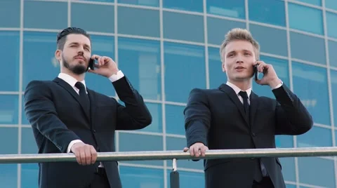 Two handsome men standing on the terrace and talking on their phones, then one Stock-Footage 69157853
