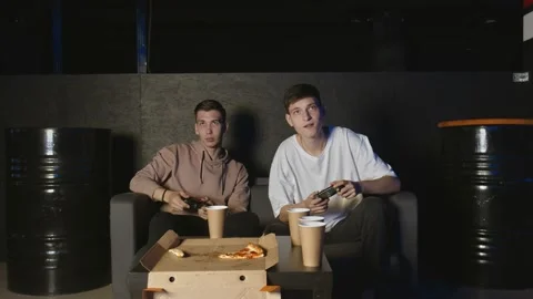 Two handsome young guys playing video games eating pizza Stock Footage 136340480