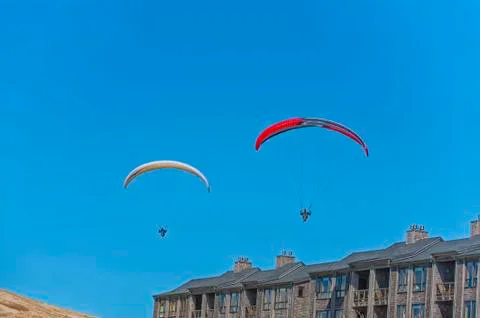 Two hang gliders glide over condos at Pacific City Stock-Fotos