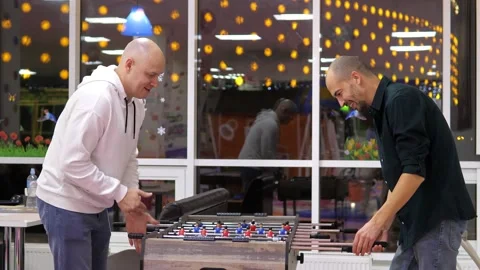 Two happy and joyful friends together playing table football in the playing Stock Footage 228678635