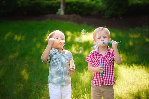 Two happy boy play in bubbles outdoors Stock Photos