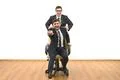 The two happy businessmen with a chair fun on the white wall background Photo