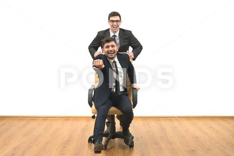 The two happy businessmen with a chair fun on the white wall background Stock Photos