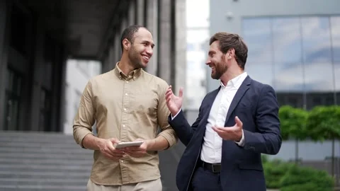 Two happy businessmen communicate while walking outside near office building.  库存影片 309644770