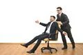 The two happy businessmen ride on the chair on the white wall background Photo