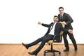 The two happy businessmen ride on the chair on the white wall background Photo