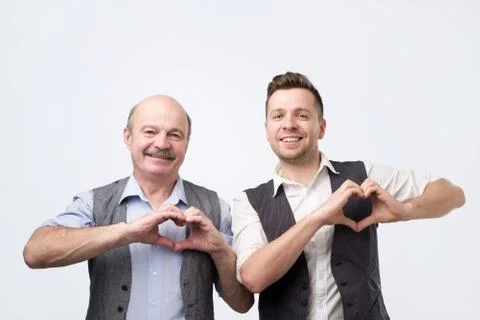 Two happy caucasian men show heart gesture with hands. Stock Photos