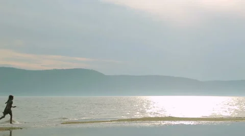 Two happy children playing on the beach at the sunset time. Two kids silhouettes Stock Footage 64863530