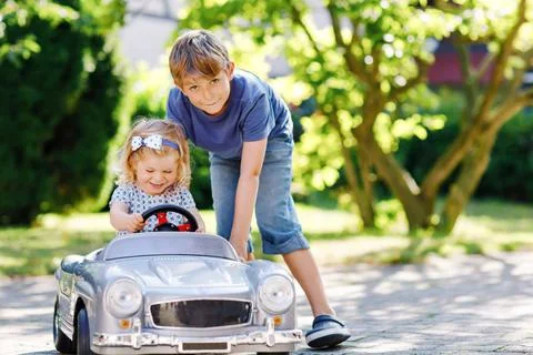 Two happy children playing with big old toy car in summer garden, outdoors. Boy Stock Photos