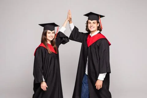 Two happy college graduates giving high five smiling after receiving diplomas Stock Photos