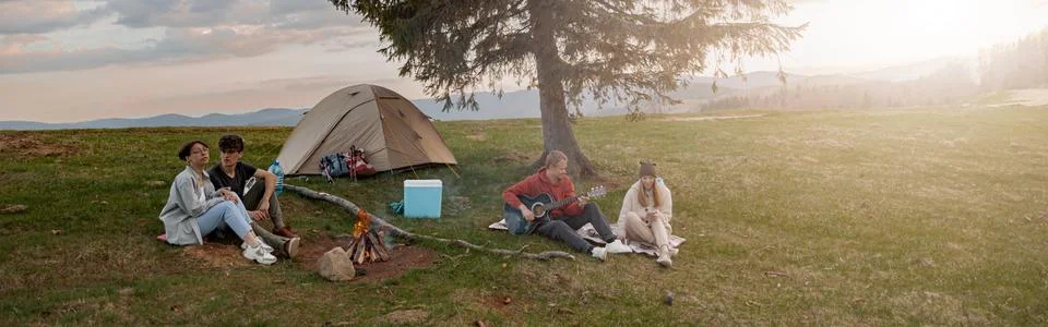 Two happy couples having fun with music at vamp site in mountains. On rural tour Foto stock