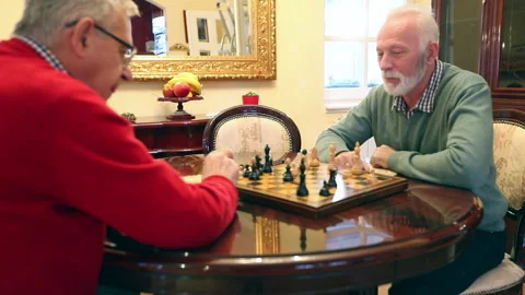 Two happy elderly friends in nursing home playing chess Stock Footage 317879308