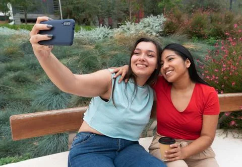 Two happy female friends taking a selfie photo with phone. Young Native American Stock Photos