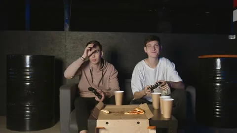 Two happy friends playing action video game in the living room sitting on the Video stock 136340697