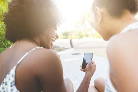 Two happy friends using smartphone outside laughing Stock Photos