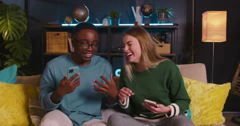 Two happy fun young multiethnic friends use smartphones playing games and Video stock 171363859