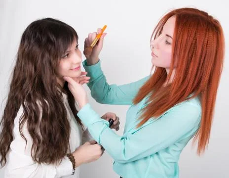Two happy girlfriends doing makeup to each other Stock Photos
