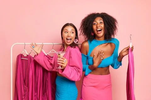 Two happy girlfriends posing inside, Asian girl holds martini glass, African Foto stock