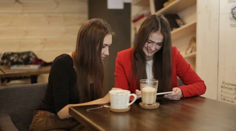 Two happy girlfriends with tablet smile in cafe Video stock 57232892