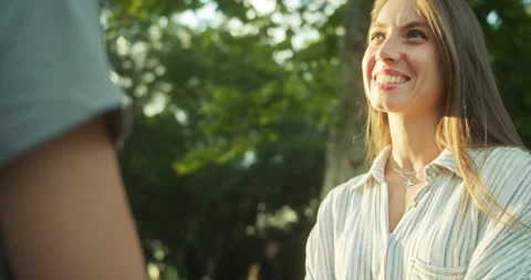 Two happy girls holding hands and chatting during their happy date in the park Stock Footage 283824341
