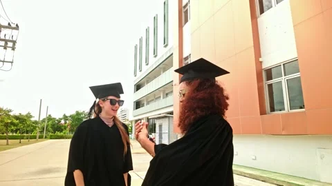 Two happy graduates in caps and gowns take a celebratory selfie outdoors. Stock-Footage 313478453