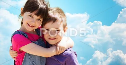 Two happy kids hugging over blue sky and clouds Stock Photos