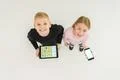 The two happy kids stand with devices. View from above Photo