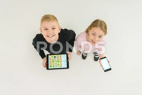 The two happy kids stand with devices. View from above Stock Photos