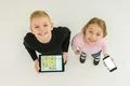 The two happy kids stand with devices. View from above Photo