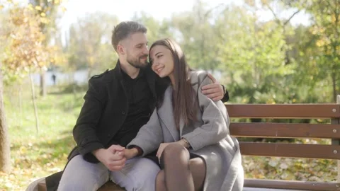 Two happy lovers sitting on park bench holding hands in cinematic style. Stock Footage 332764026