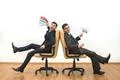 The two happy men with papers sit on chairs on the white wall background Photo