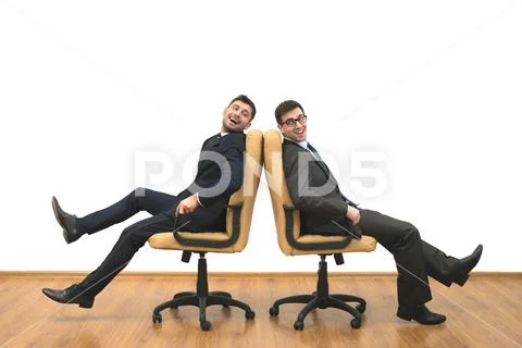 The two happy men sit on chairs on the white wall background Stock Photos